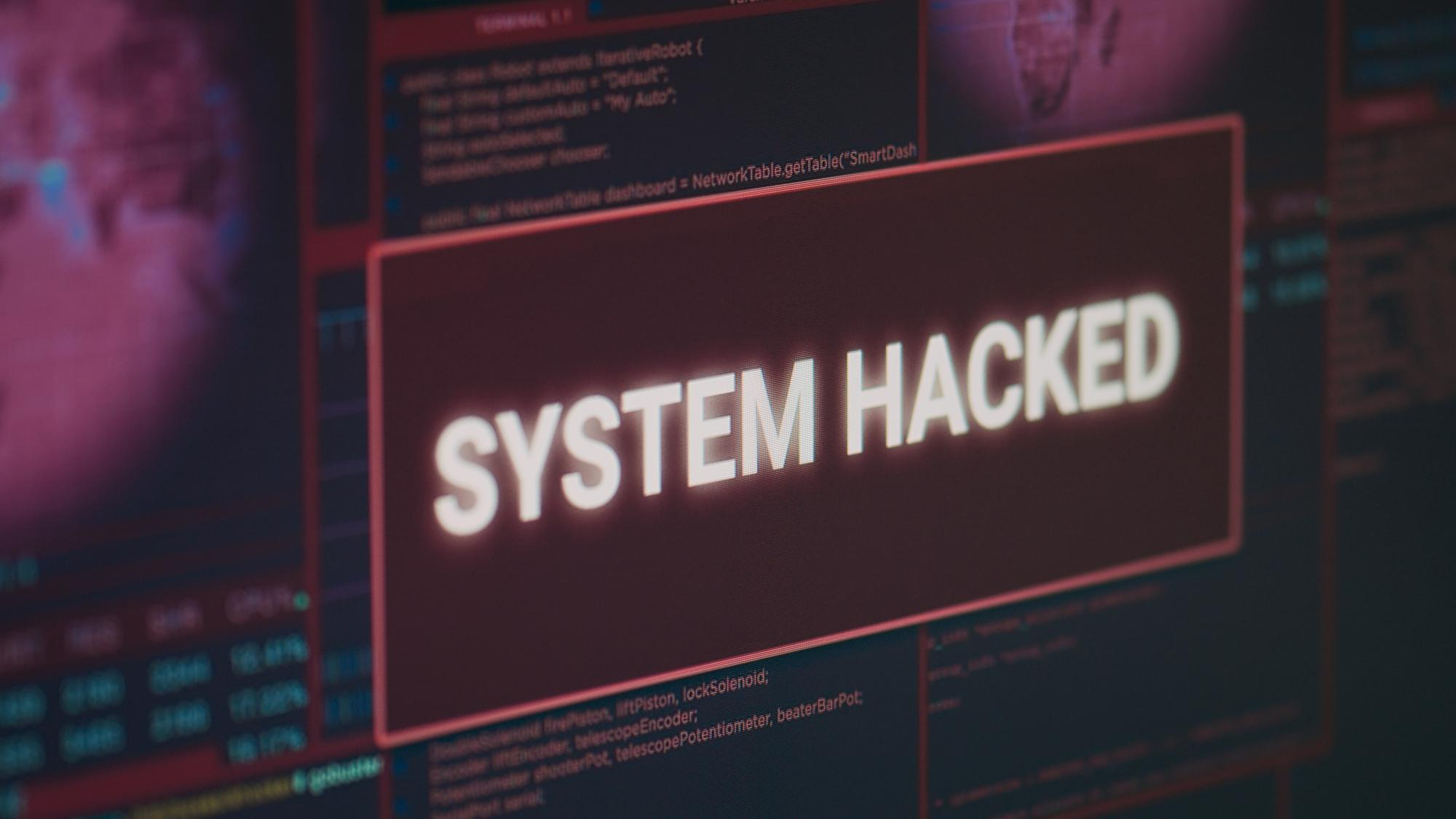 immagine di uno schermo con al centro un rettangolo rosso e la scritta "system hacked"